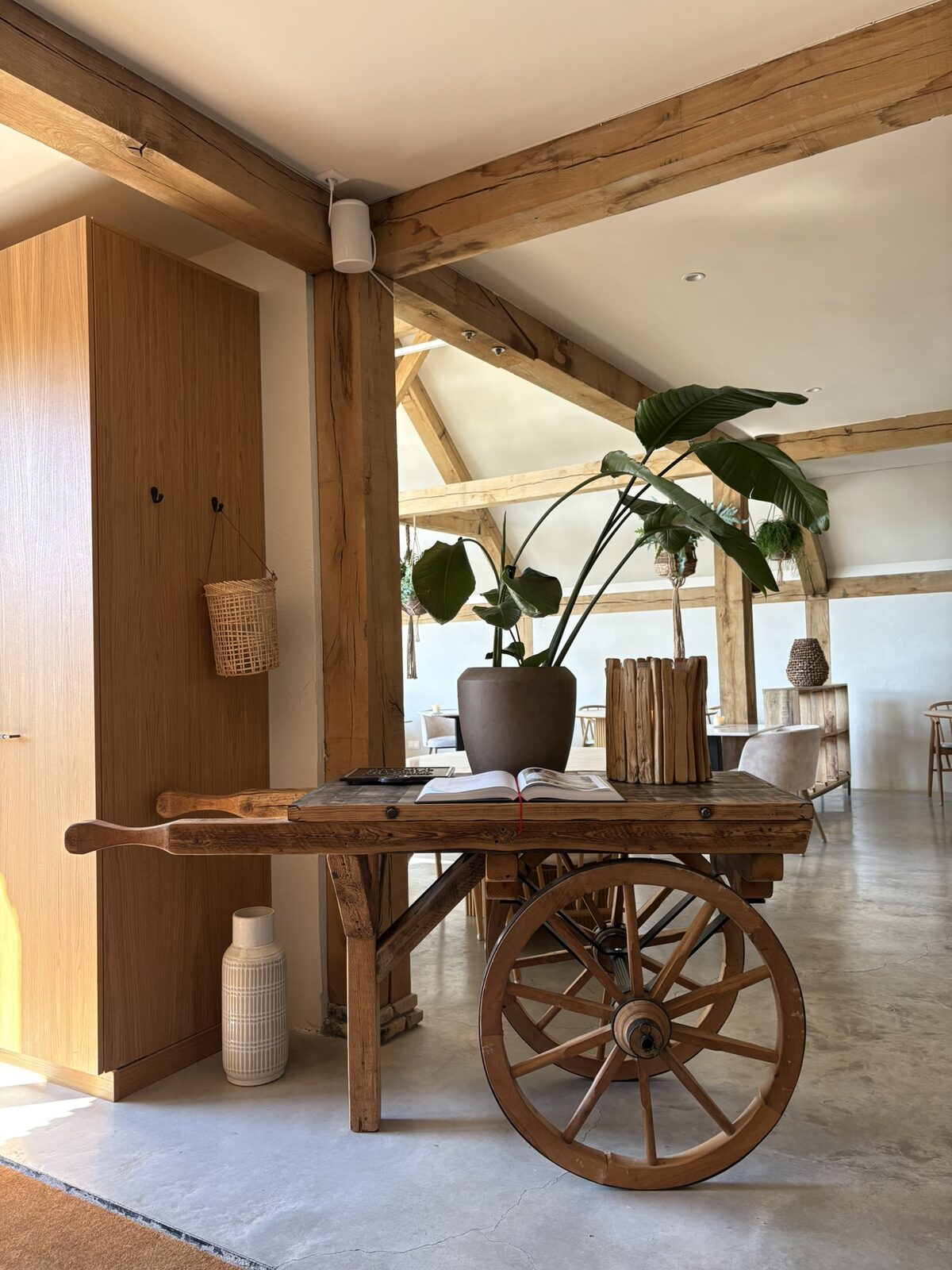 Sfeervol interieur in Oosterend: houten balken, een vintage handkar als tafel en grote planten.