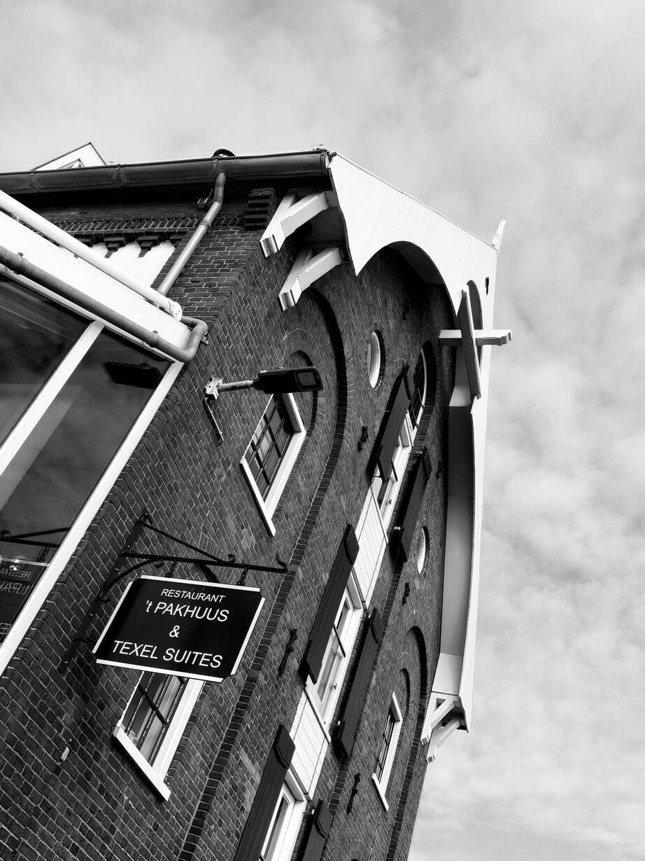 't Pakhuus & Texel Suites: zwart-wit foto van het monumentale pand in de haven van Oudeschild.